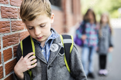Pupils friends teasing a pupil alone primary school photo