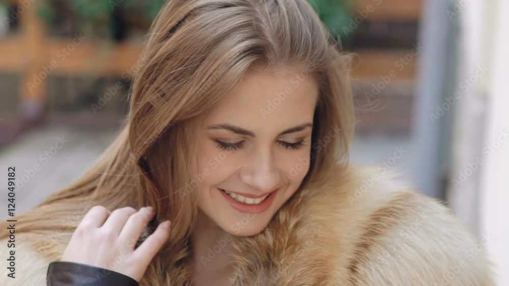 Close up of cute girl smiling in furry jacket on the street. Slow motion Close up of cute girl smiling in furry jacket on the street. Slow motion