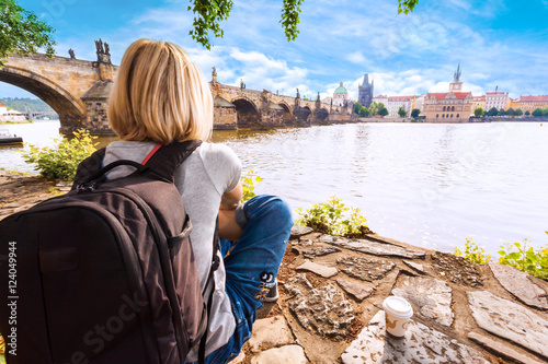 Female traveler enjoys views of the Charles Bridge in Prague. Czech Republic. Charles Bridge with its statuette, Old Town Bridge Tower, St. Francis Of Assissi Church in the background. photo