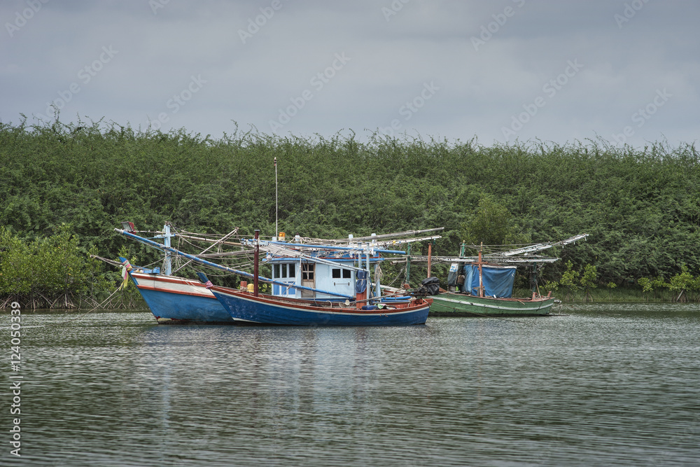 traditional fishing boat on the sea with mangrove forest in background.cloudy sky.filtered image.selective focus traditional fishing boat on the sea with mangrove forest in background.cloudy sky.filtered image.selective focus