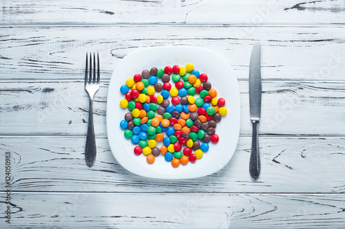 A lot of vitamins, candy and pills on a big white plate. Medications for lunch.
