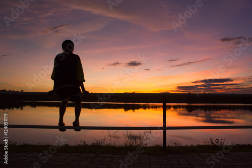 silhouette woman sitting alone on fence look at the sky
