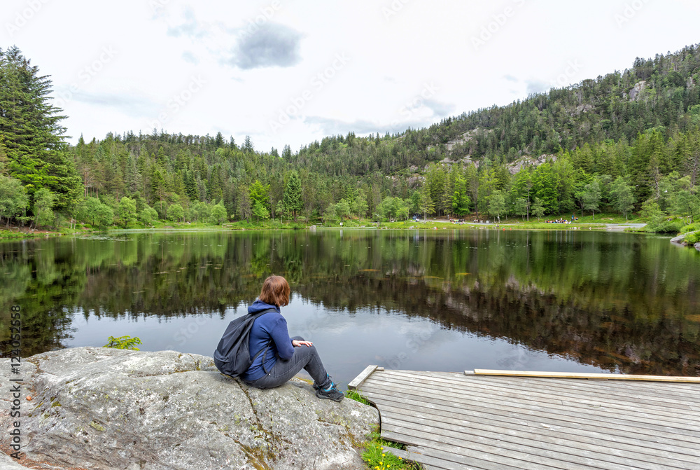 Alone young girl sitting near by beautiful blue lake