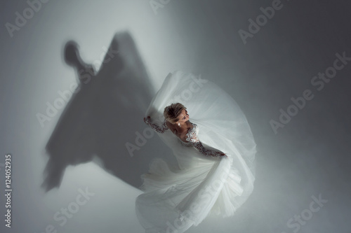 Beautiful attractive bride in wedding dress with long full skirt, white background, dance and smile, top view