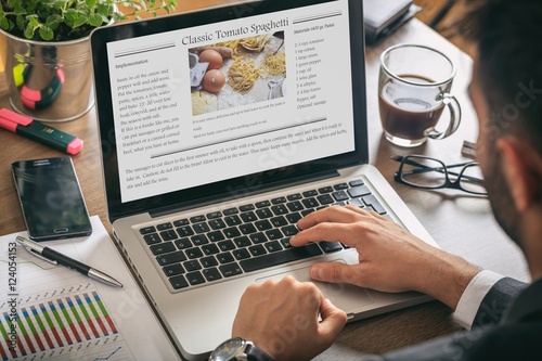 Man working on a laptop - recipe on the screen