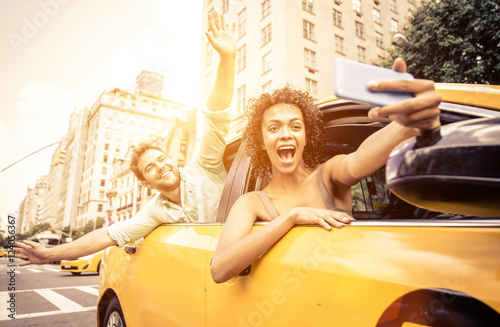 Happy couple driving in New york on a yellow cab and taking self