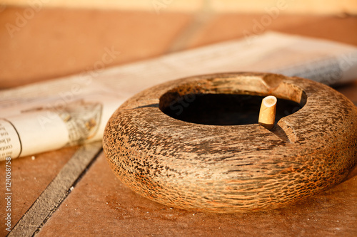 Wooden ashtray and newspaper on the terrace at sunrise