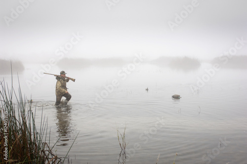 Hunter wading in water wearing camouflage clothing photo