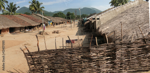 Thatched huts line the central streeet of a tribal village photo