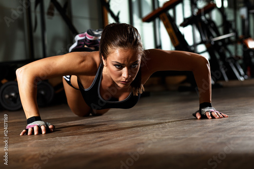 Sporty young woman doing a push-ups at gym.