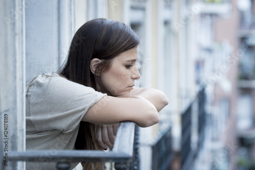 young sad beautiful woman suffering depression looking worried and wasted on home balcony