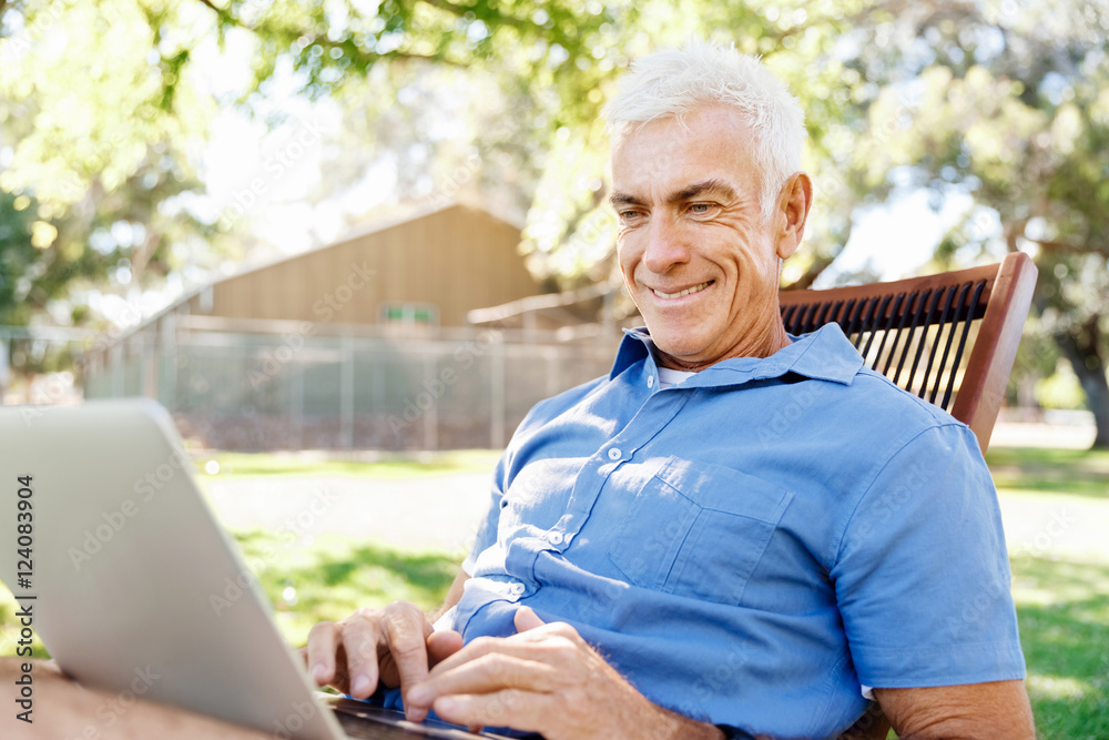 Senior man with notebook sitting in the park Senior man with notebook sitting in the park