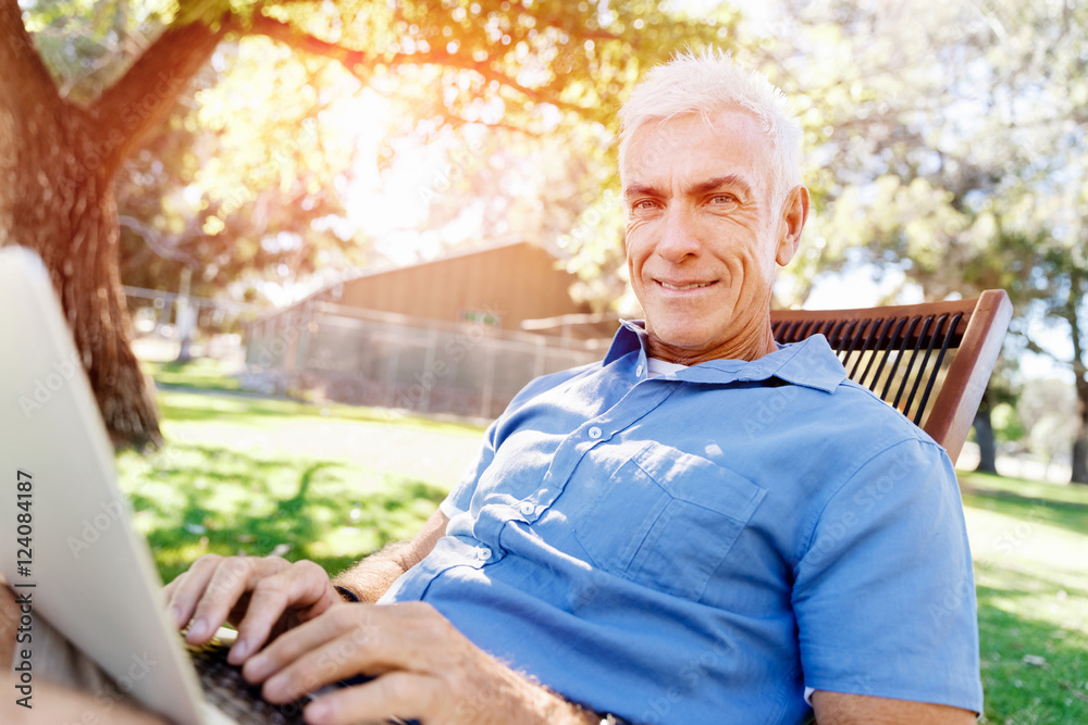 Senior man with notebook sitting in the park Senior man with notebook sitting in the park