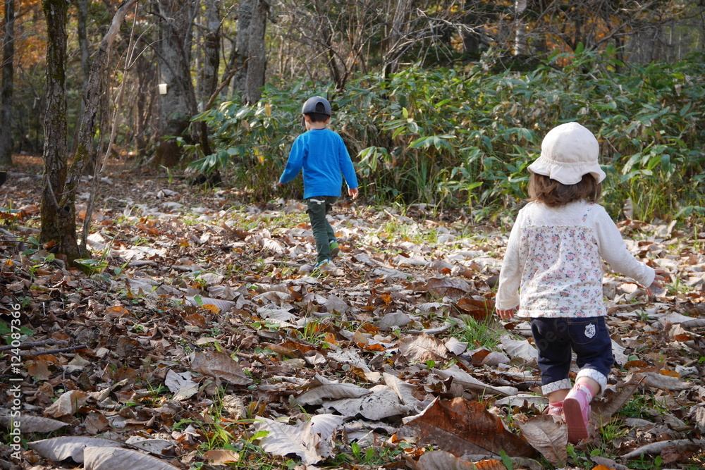 Fototapeta premium Young children running in forest in autumn