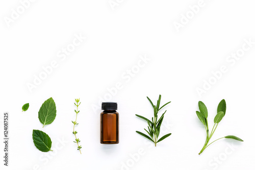 Bottle of essential oil with  fresh herbal sage, rosemary, thyme photo