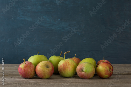 Many apples on wooden table on blue background