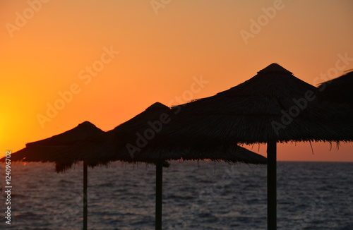 Obraz na płótnie Tropical sunset with beach umbrellas and sea w salonie
