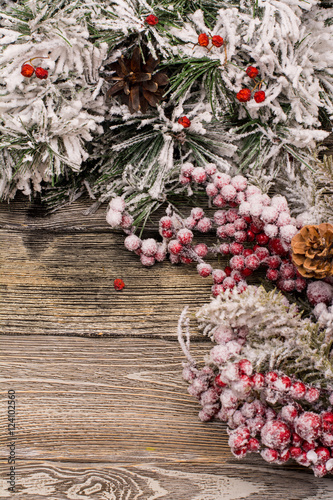 Fir branch and berries in snow, cone on wooden background. Christmas theme. Template