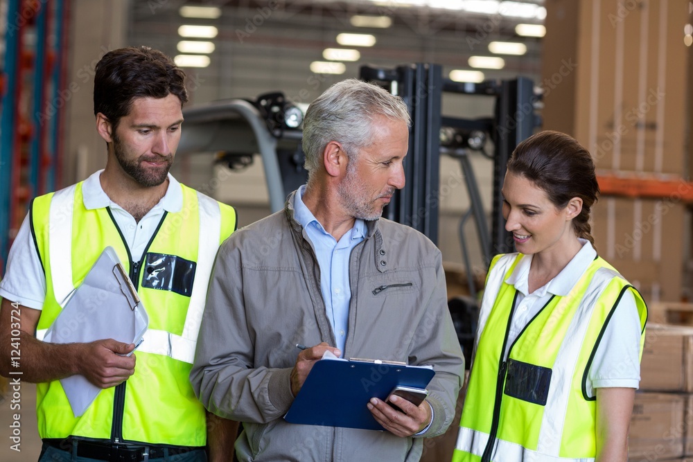 Warehouse manager and workers discussing with clipboard Warehouse manager and workers discussing with clipboard