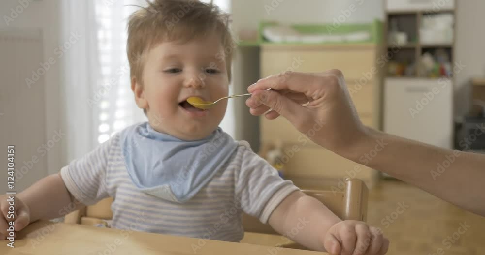 POV shot of an adorable playful baby being fed with baby food.
POV shot of an adorable playful baby being fed with baby food.