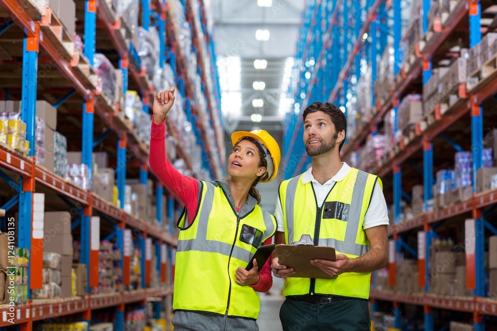 Warehouse workers discussing with clipboard while working Warehouse workers discussing with clipboard while working