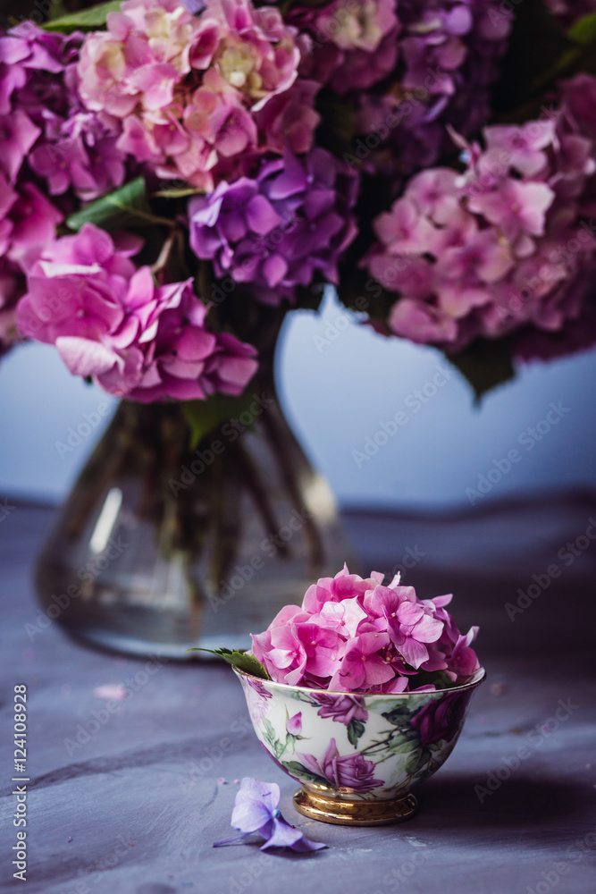 Teacup with hydrangea flower stands before the vase