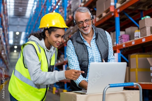 Warehouse manager and female worker using laptop