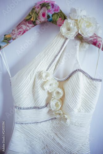 Stylish wedding dress decorated with cloth flowers hangs on pink