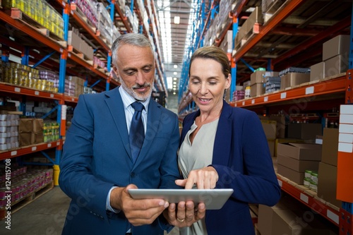 Warehouse manager and client discussing over digital tablet