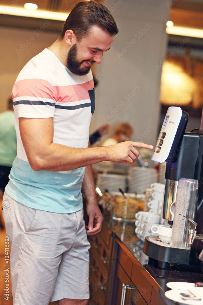 Attractive man using coffee machine in hotel