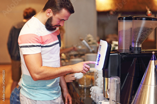 Attractive man using coffee machine in hotel