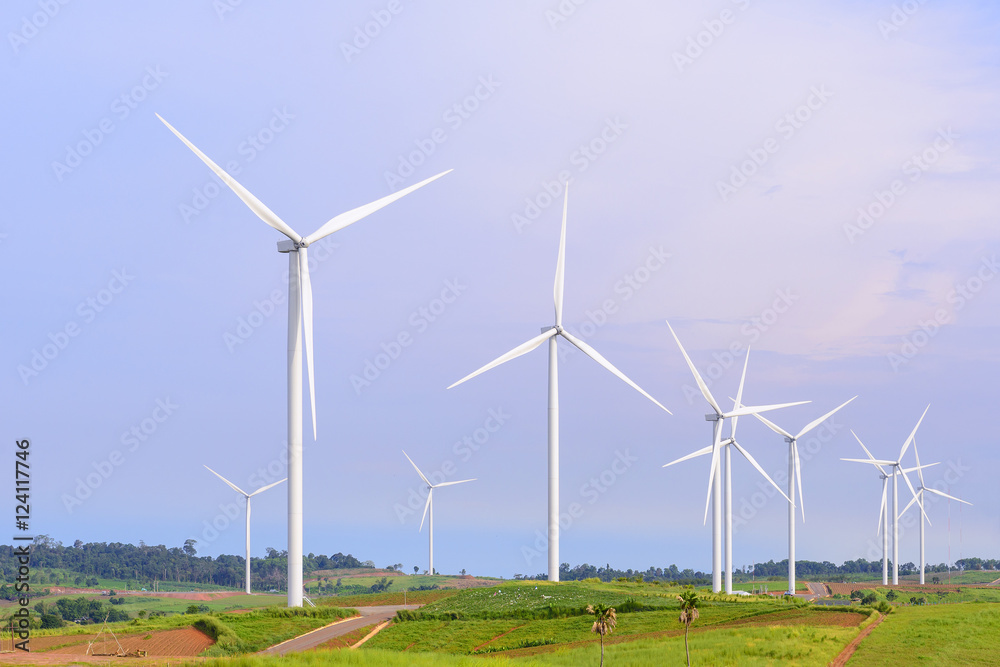 The big windmill turbine field with the grass foreground and the blue sky. The big windmill turbine field with the grass foreground and the blue sky.