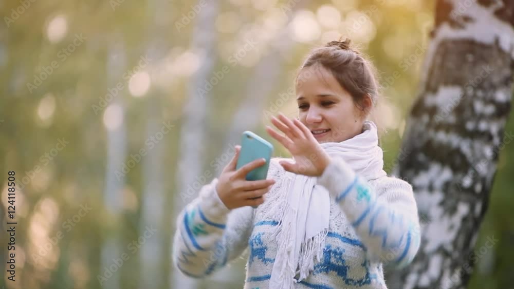 Smiling woman in a knitted sweater and scarf making selfie with mobile phone in park during the autumn. 1920x1080 Smiling woman in a knitted sweater and scarf making selfie with mobile phone in park during the autumn. 1920x1080