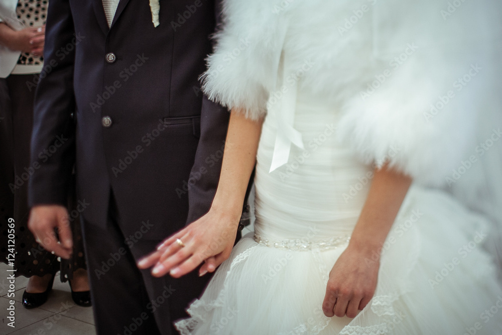 Man holds a gand of a bride dressed in white fur