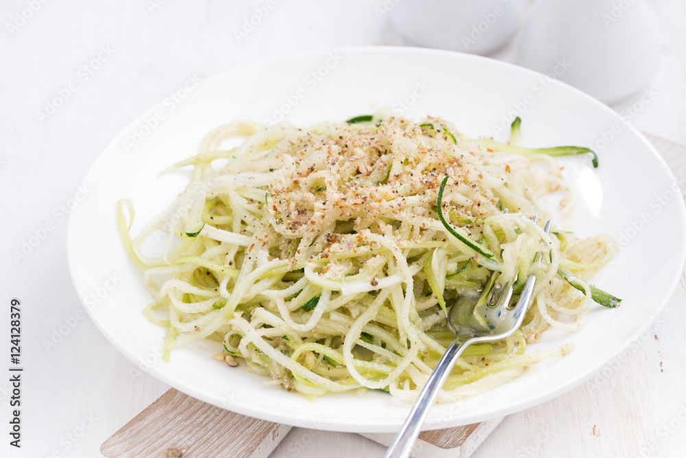 vegetarian pasta with zucchini and nuts on white table
