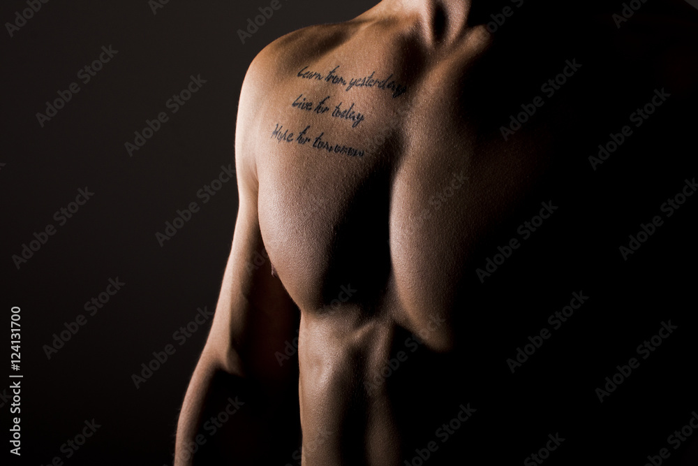 Naklejka premium Sexy Muscular Man Tattooed Torso on Black Background. Male Chest Close Up.