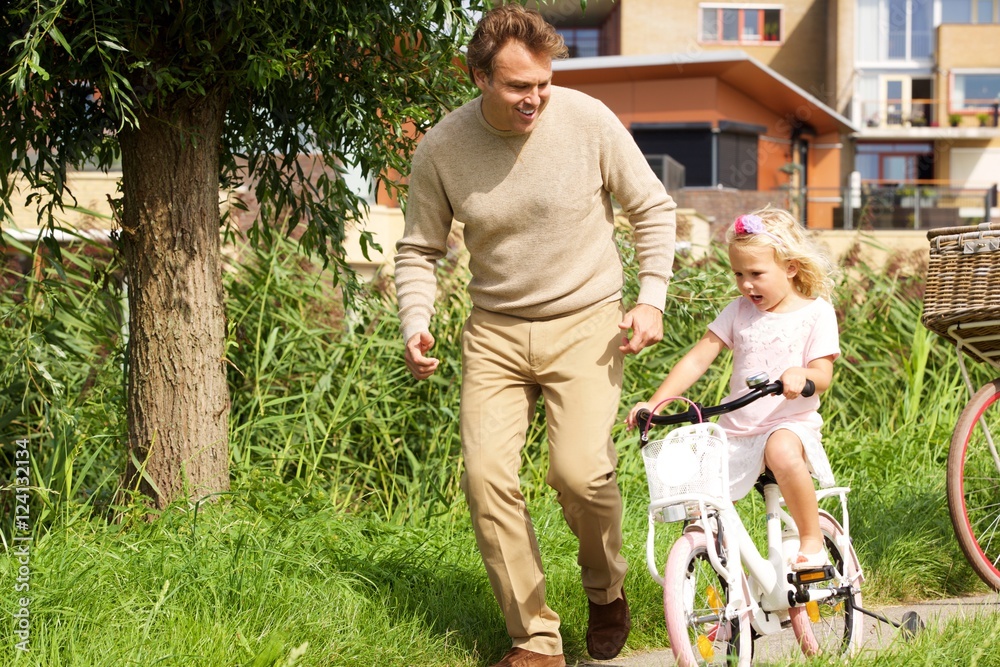 Fototapeta premium Father teaching her daughter cycling