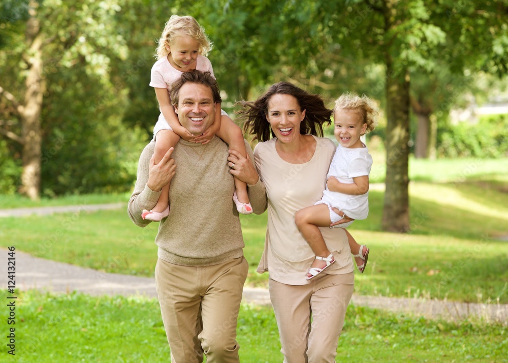 Fototapeta premium Happy beautiful family of four running in park