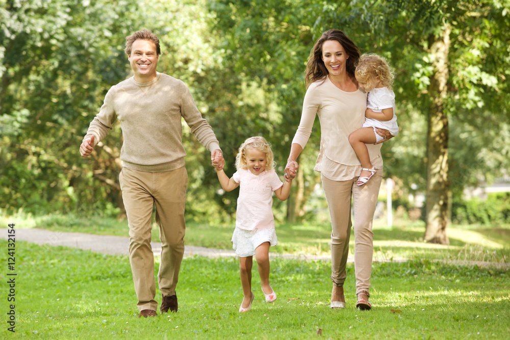 Fototapeta premium Happy young family of four walking in the park