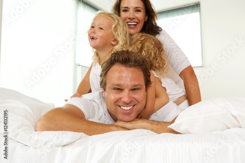 Happy young family enjoying in bed © mimagephotos