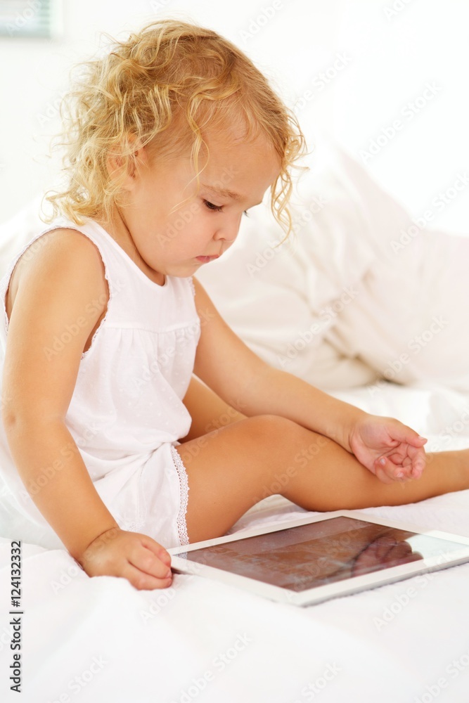 Innocent little girl on bed with digital tablet Innocent little girl on bed with digital tablet