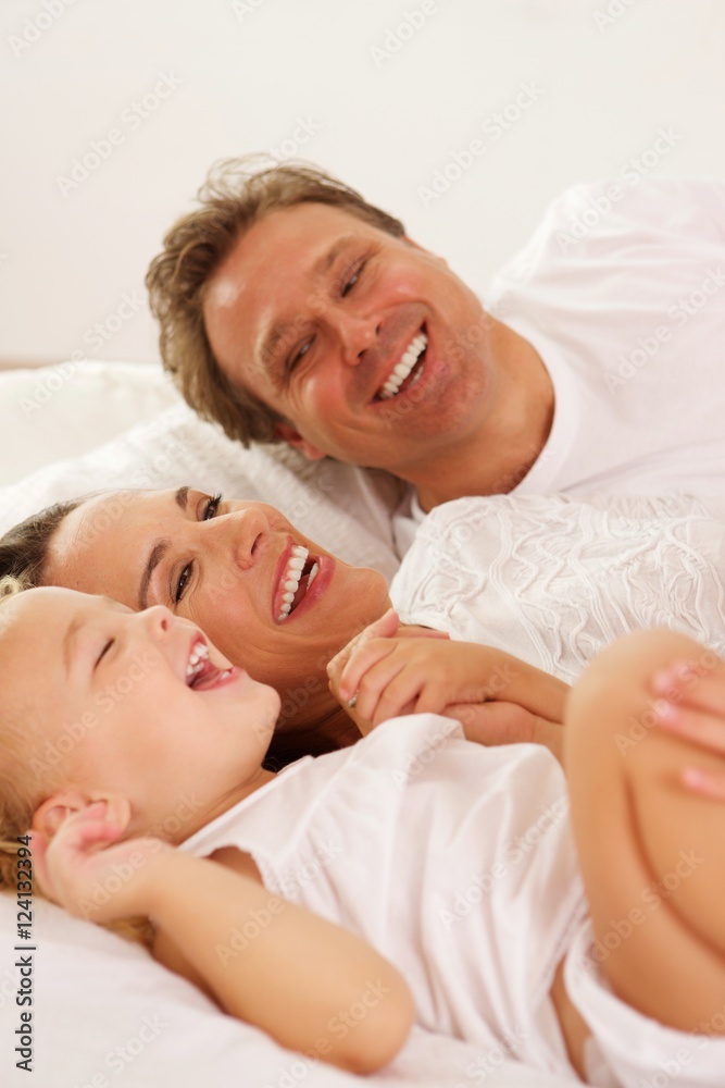 Smiling young family lying on bed at home Smiling young family lying on bed at home