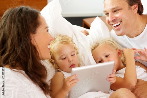 Happy parents with daughters using digital tablet