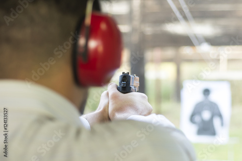 Shooting with Gun at Target in Shooting Range. Man Practicing Fire Pistol Shooting.