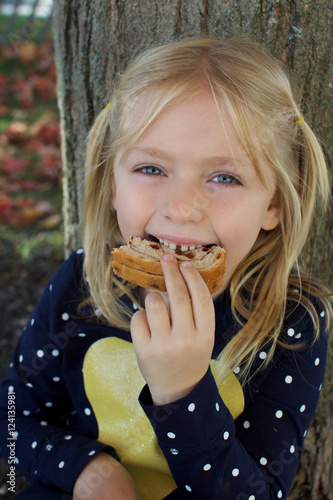 adorable young school age girl eating a peanut butter sandwich