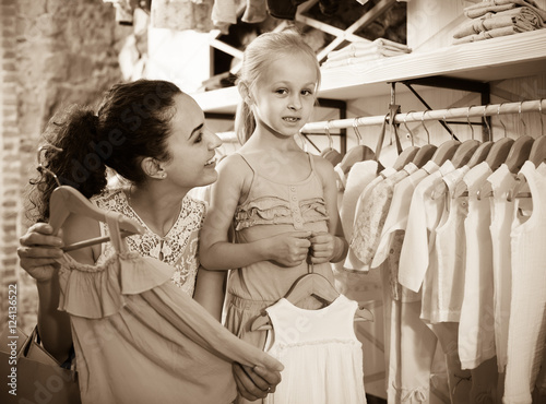 portrait of woman and girl shopping white baby apparel in cloth