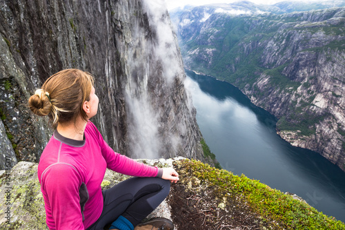 Young woman hiking on kjerag. Happy girl enjoy beautiful lake and good weather in Norway.