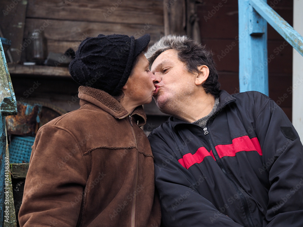 Fototapeta premium Man kisses a woman. People aged. Old wooden house
