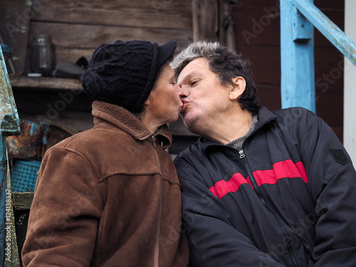 Man kisses a woman. People aged. Old wooden house