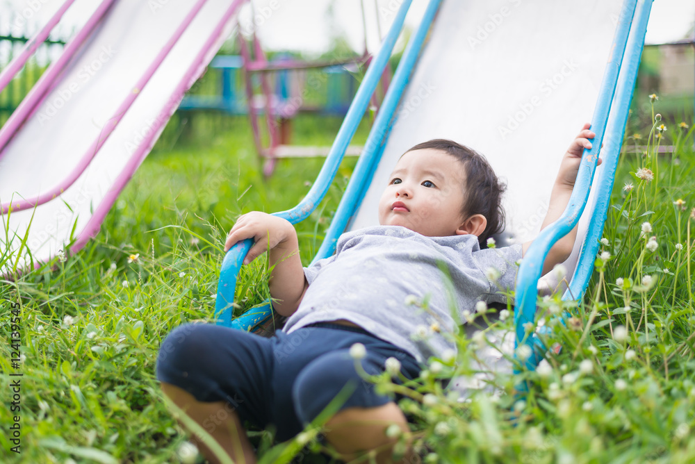 Little Asian kid playing slide at the playground